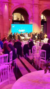 Salle de réception avec tables rondes et écran vidéo lors d'un événement Axa